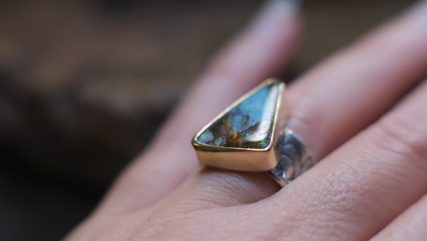 Striking electric blue opalised fossil wood set in 9ct Gold on piratey textured silver band