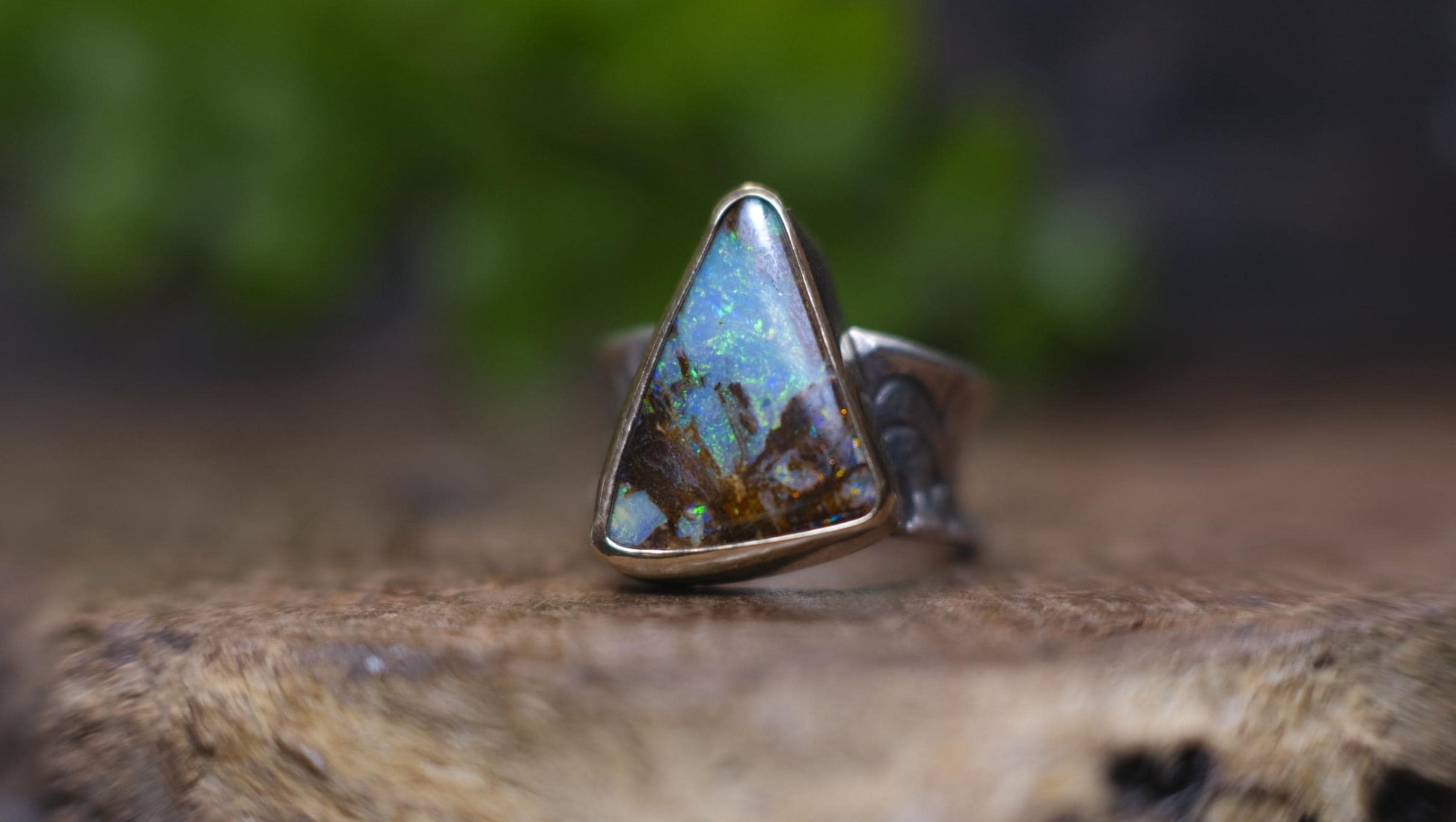 Striking electric blue opalised fossil wood set in 9ct Gold on piratey textured silver band