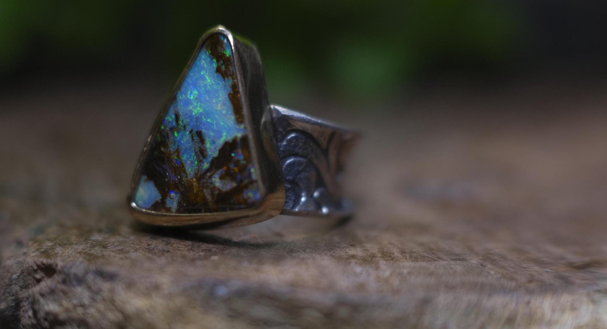 Striking electric blue opalised fossil wood set in 9ct Gold on piratey textured silver band