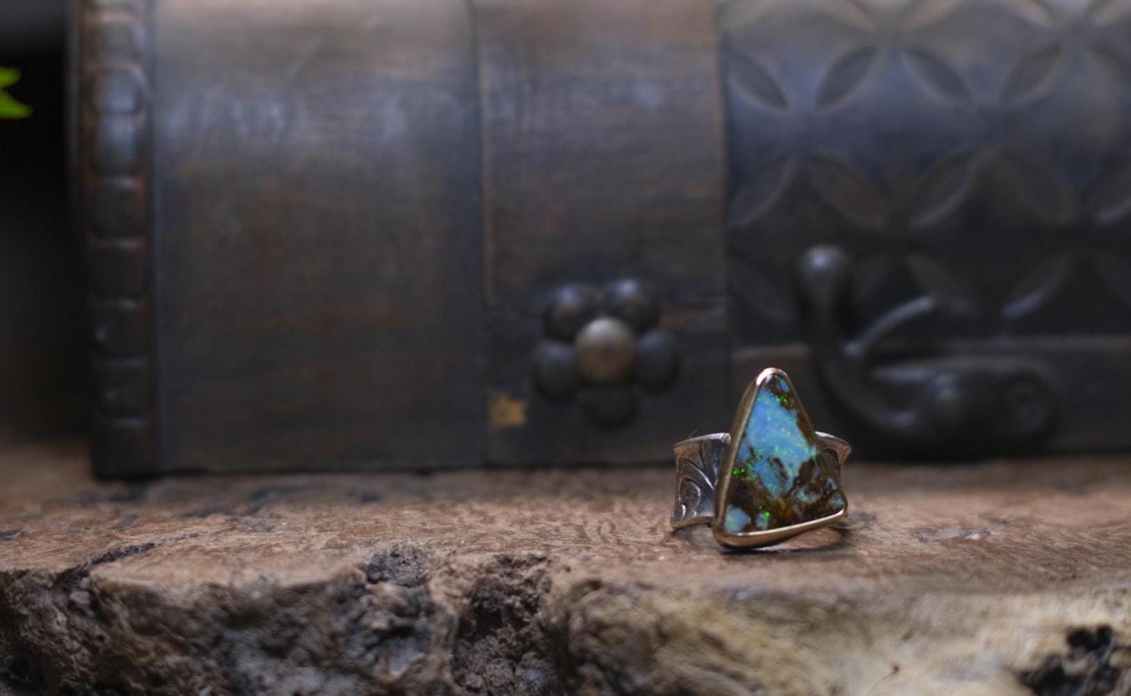 Striking electric blue opalised fossil wood set in 9ct Gold on piratey textured silver band