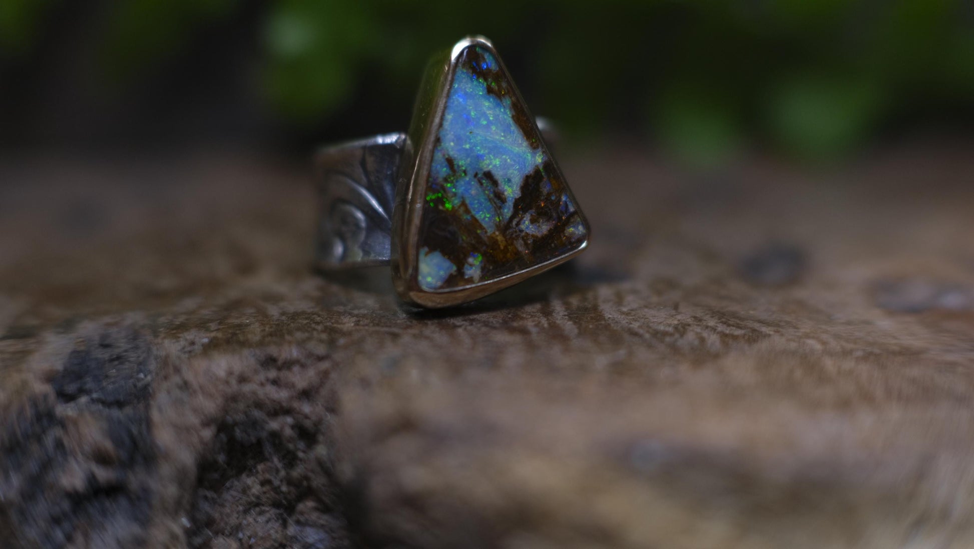 Striking electric blue opalised fossil wood set in 9ct Gold on piratey textured silver band