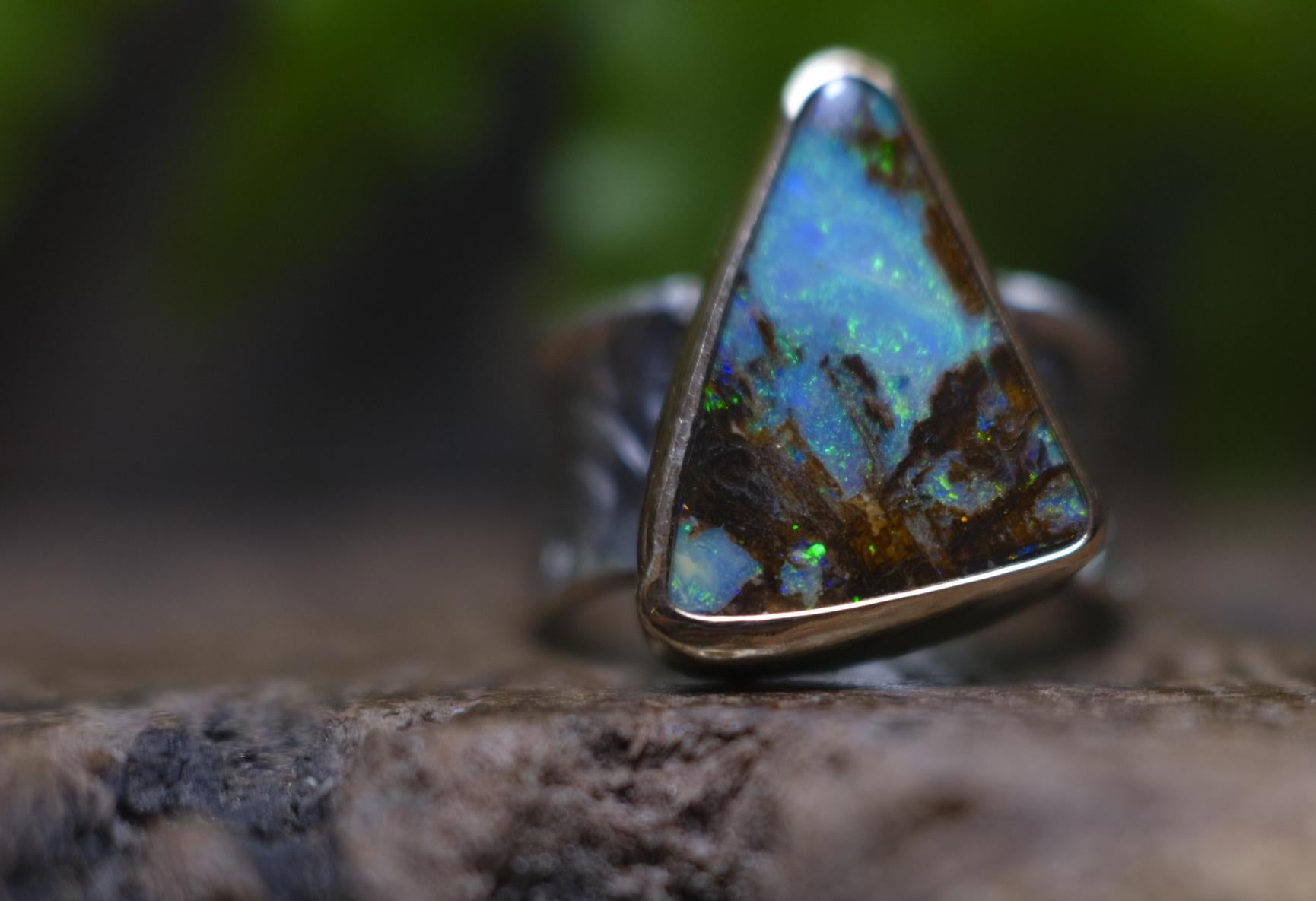 Striking electric blue opalised fossil wood set in 9ct Gold on piratey textured silver band