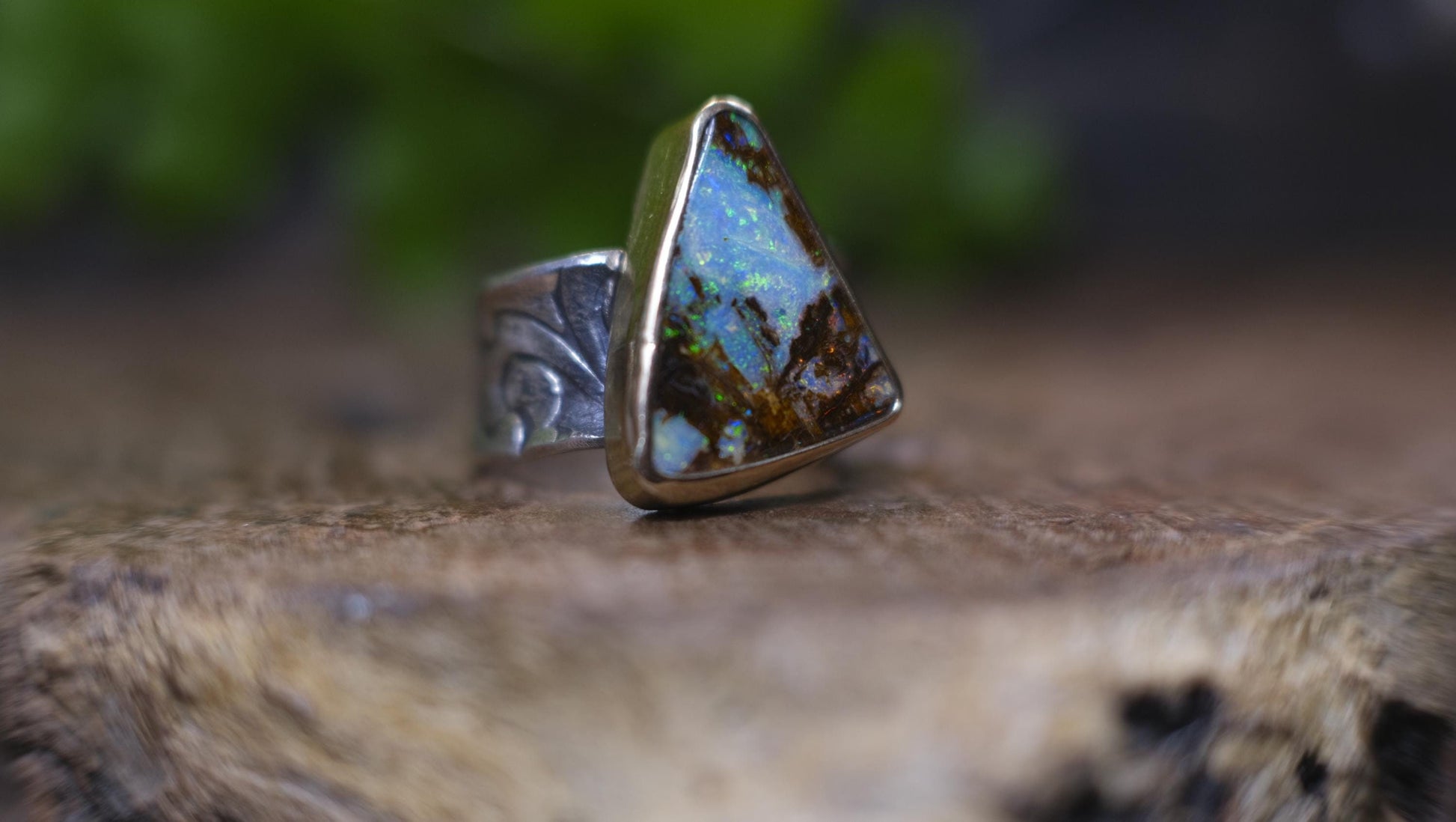 Striking electric blue opalised fossil wood set in 9ct Gold on piratey textured silver band